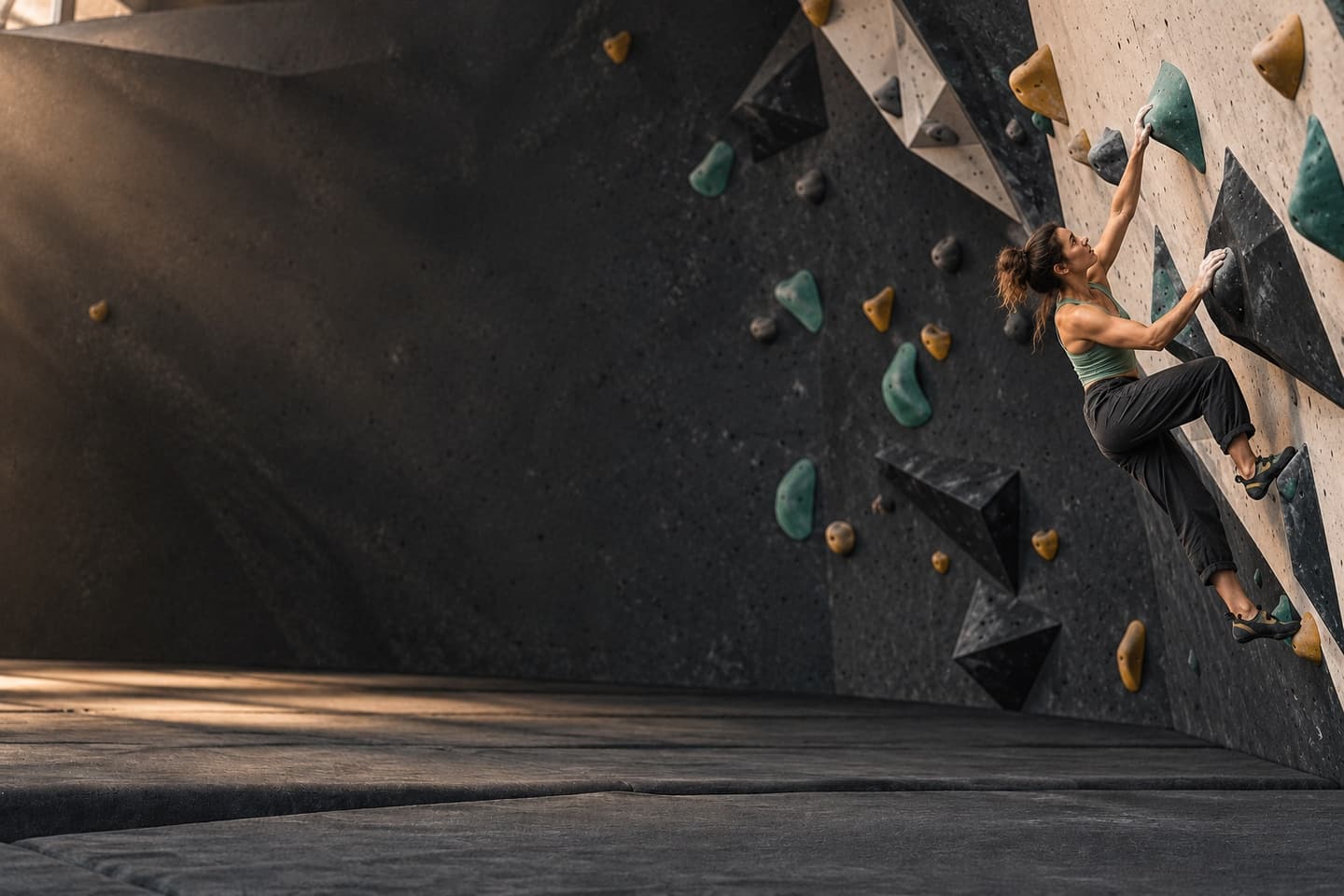 A climber reaching between holds on a modern indoor bouldering wall